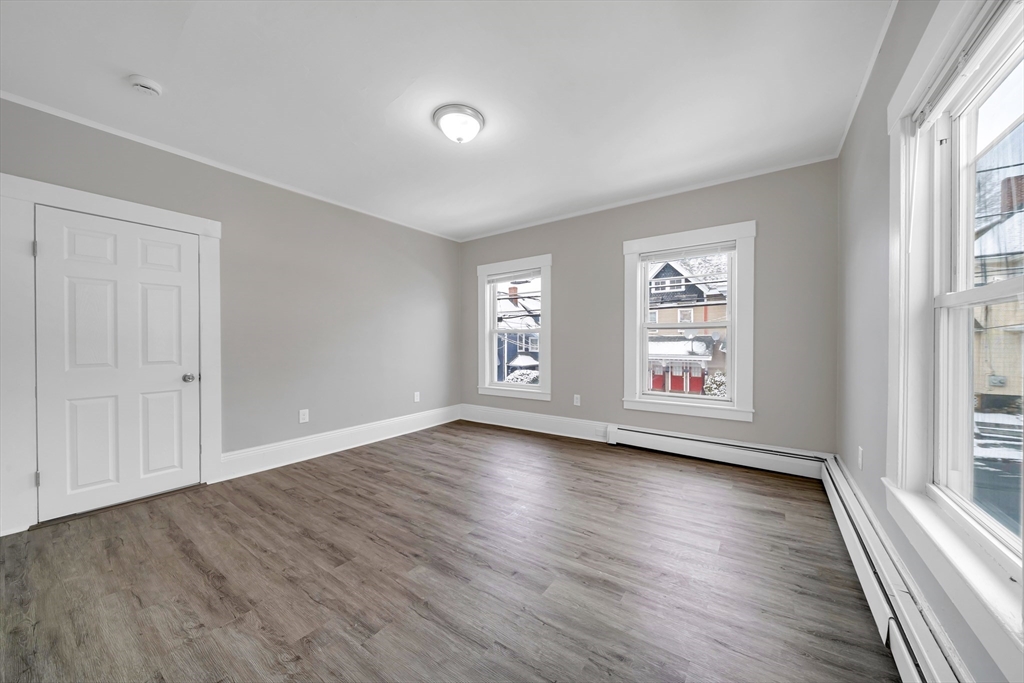 49 6th Street Lowell, MA 01850 - Photo 21 of 37 an empty room with wooden floor and windows