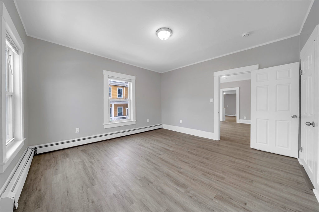 49 6th Street Lowell, MA 01850 - Photo 23 of 37 an empty room with wooden floor and windows
