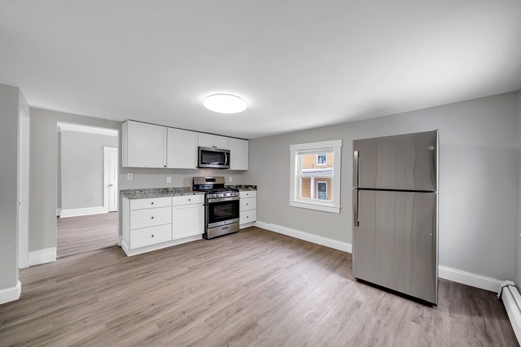 49 6th Street Lowell, MA 01850 - Photo 28 of 37 a kitchen with white cabinets and stainless steel appliances