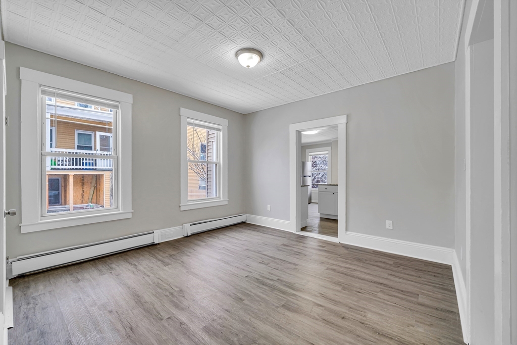 49 6th Street Lowell, MA 01850 - Photo 5 of 37 an empty room with wooden floor and windows