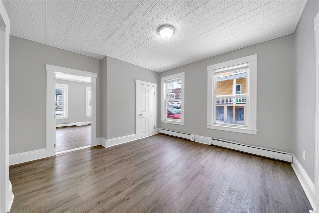 49 6th Street Lowell, MA 01850 - Photo 6 of 37 an empty room with wooden floor and windows