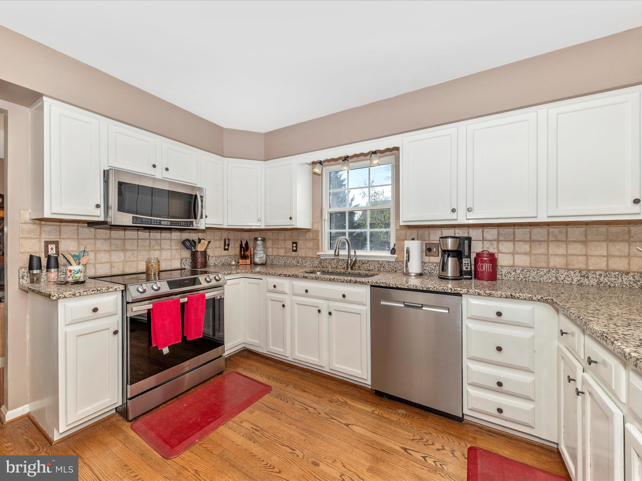 2406 Graystone Lane Frederick, MD 21702 - Photo 9 of 62 a kitchen with granite countertop a sink dishwasher stove top oven and cabinets with wooden floor
