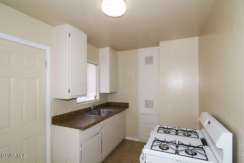 2618 Desert Street, Unit 11 Rosamond, CA 93560 - Photo 6 of 8 a kitchen with granite countertop a sink stove and white cabinets