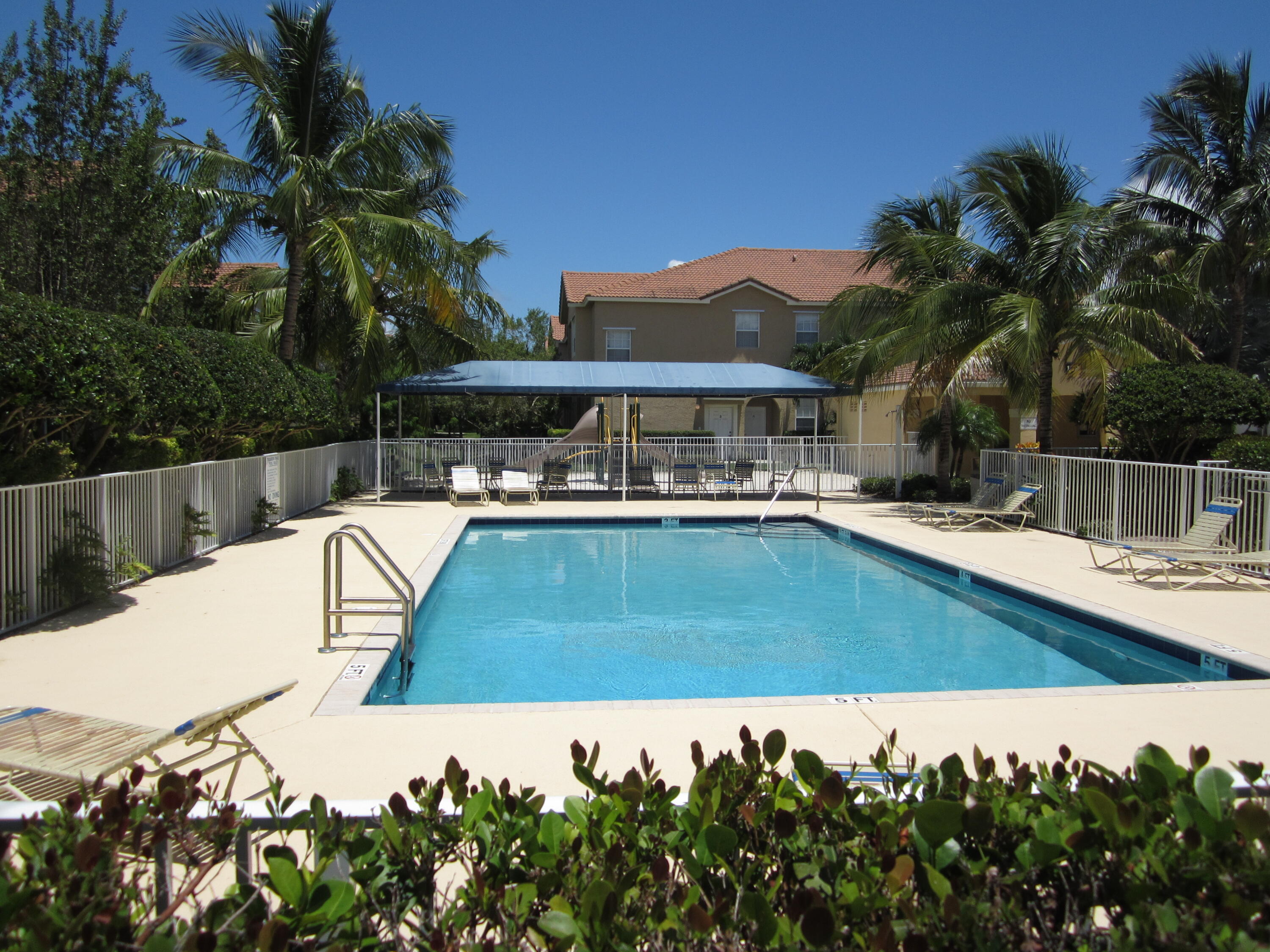 105 Lighthouse Circle, Unit J Tequesta, FL 33469 - Photo 1 of 18 a view of swimming pool with outdoor seating and house in the background