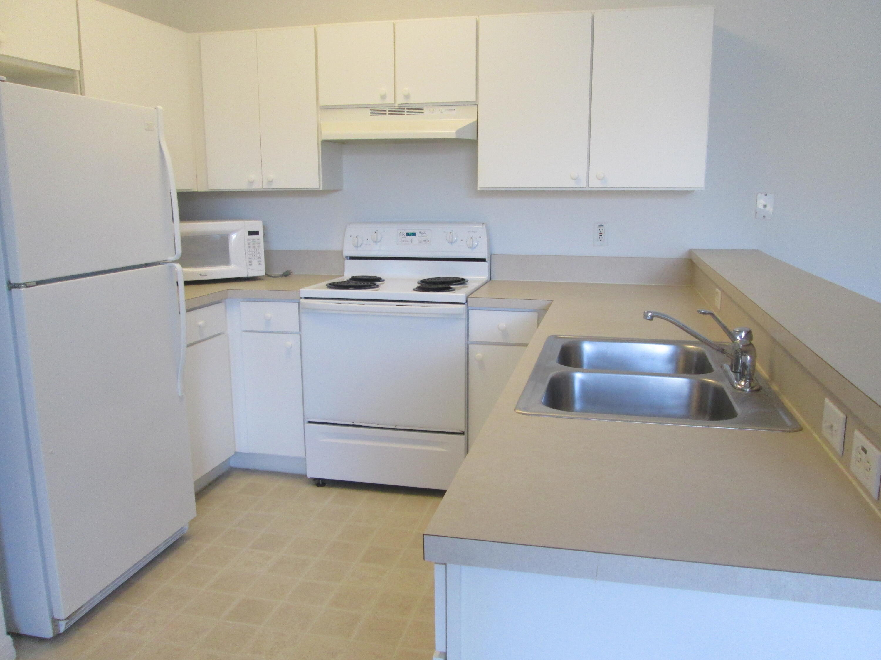 105 Lighthouse Circle, Unit J Tequesta, FL 33469 - Photo 8 of 18 a kitchen with a refrigerator sink and cabinets