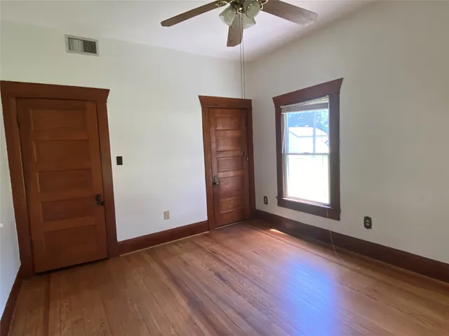 an empty room with wooden floor closet and windows
