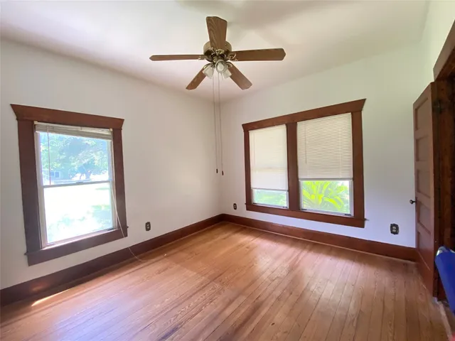 a view of an empty room with a window and wooden floor