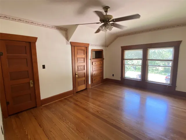 a view of empty room with wooden floor and fan