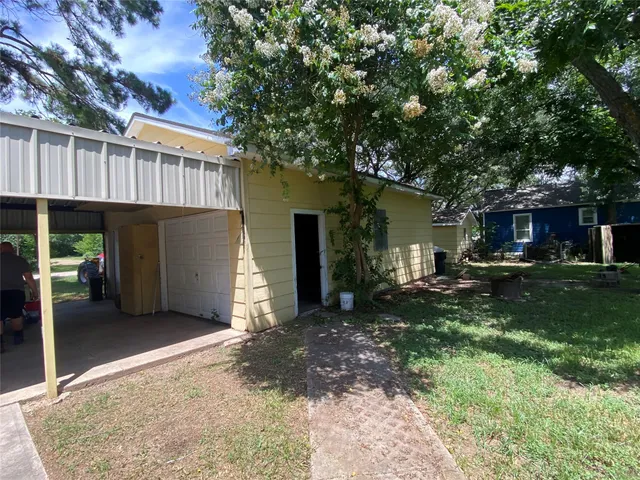 a view of a house with a yard plants and large tree
