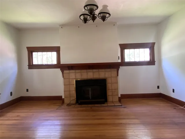 an empty room with wooden floor a fireplace and windows