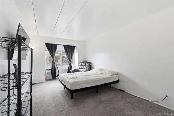 a bedroom with a bed a mirror on dresser and a flat screen tv
