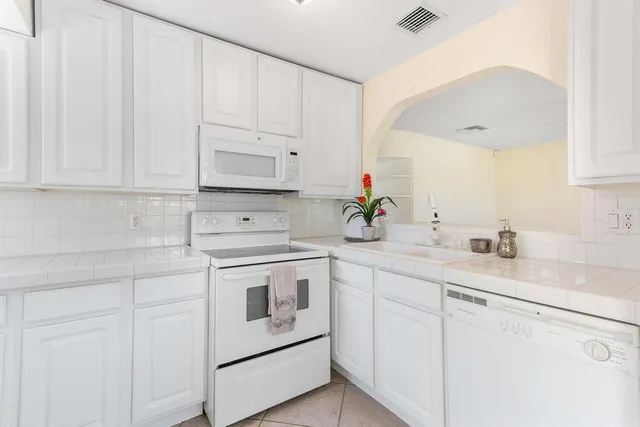 a kitchen with white cabinets and white appliances