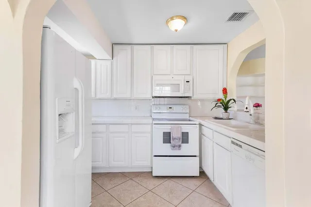 a kitchen with white cabinets and white appliances