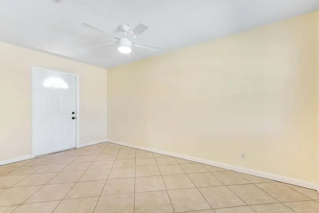 an empty room with a ceiling fan and carpet