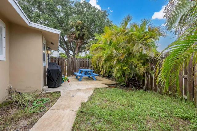 a view of a backyard with potted plants and large trees