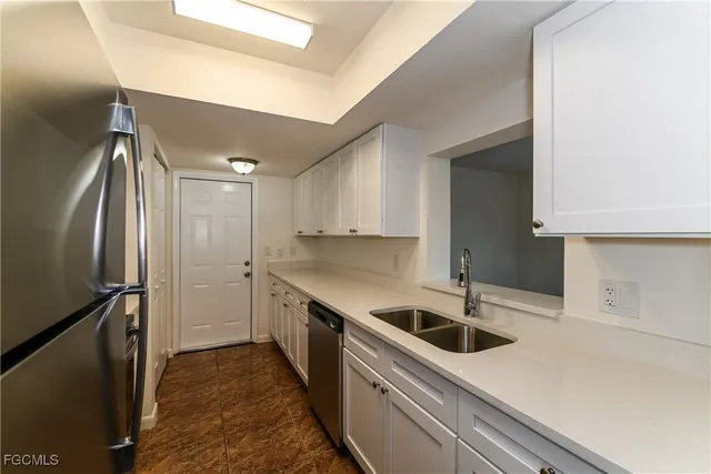 a kitchen with a sink a refrigerator and cabinets