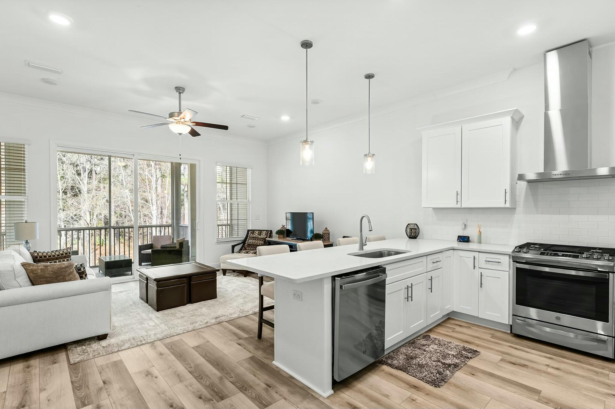 a open kitchen with stainless steel appliances granite countertop a stove a sink a refrigerator a dining table and chairs with wooden floor