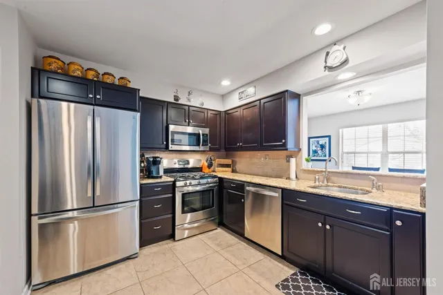 a kitchen with stainless steel appliances granite countertop a refrigerator a sink a stove a microwave and wooden cabinets