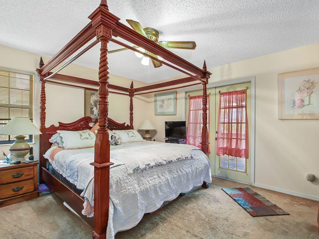 5931 Southeast Pine Drive Stuart, FL 34997 - Photo 12 of 24 a bedroom with a bed a chandelier and dresser