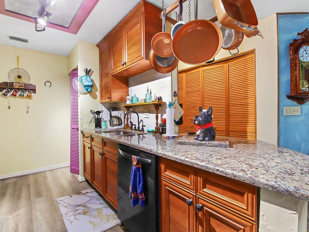 5931 Southeast Pine Drive Stuart, FL 34997 - Photo 6 of 24 a kitchen with stainless steel appliances granite countertop a sink and a wooden floor