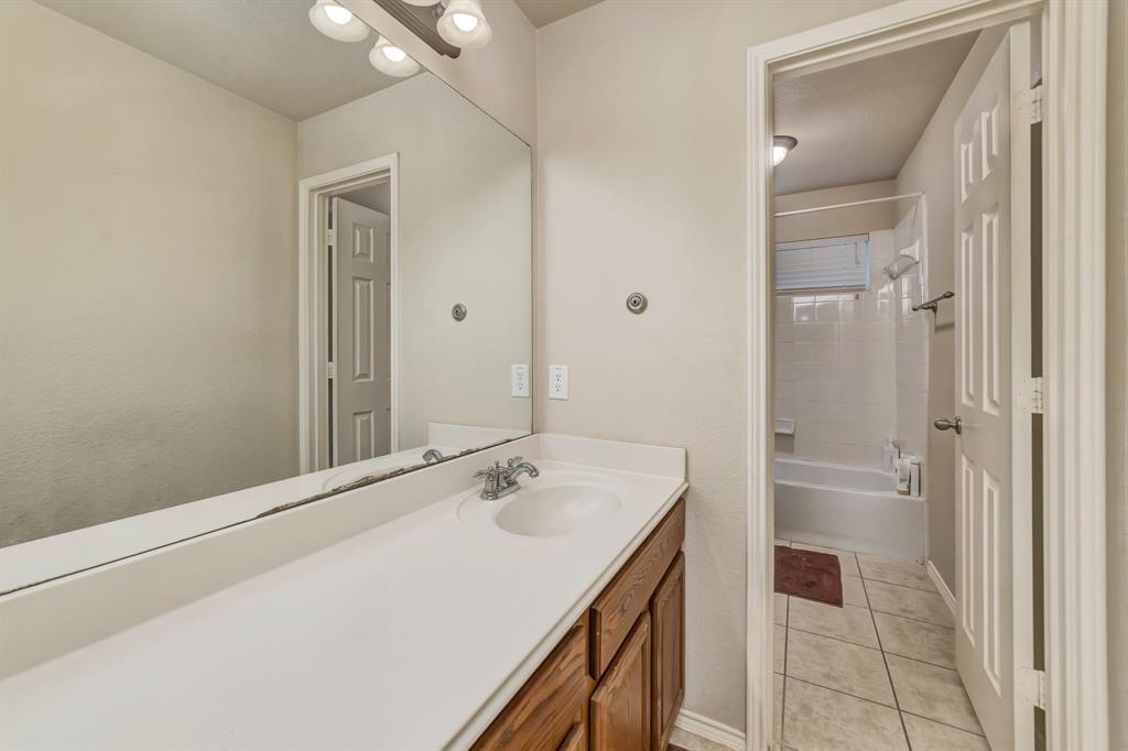 2312 Tawny Owl Road Grand Prairie, TX 75052 - Photo 28 of 40 Bathroom vanity with a white countertop and integrated sink, chrome faucet, and wood-finish cabinetry