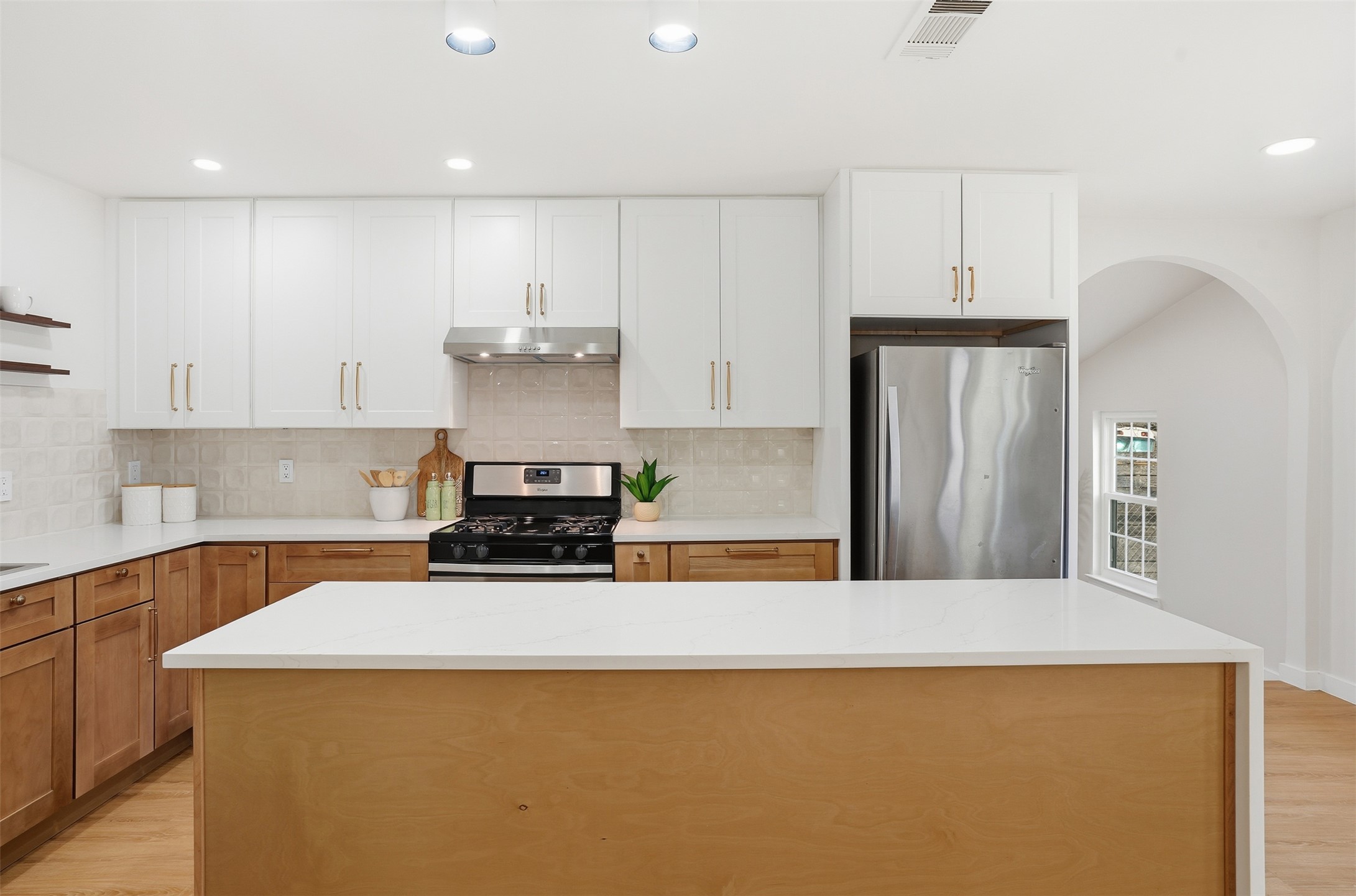 5601 Samuel Huston Avenue Austin, TX 78721 - Photo 11 of 24 Kitchen featuring light wood-style flooring, stainless steel appliances, light stone counters, a kitchen island, and recessed lighting