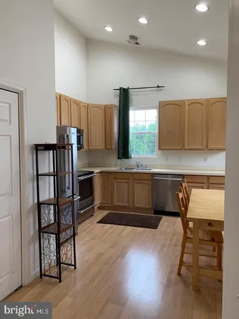 a kitchen with stainless steel appliances kitchen island granite countertop wooden cabinets a dining table and chairs