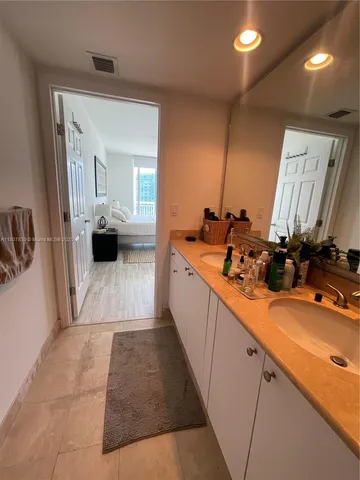 a large white kitchen with a sink and large mirror next to a window