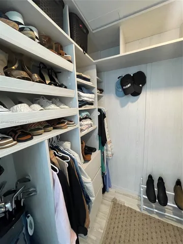 a view of walk in closet with clothes and shoes