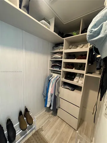 a view of walk in closet with clothes and shoes