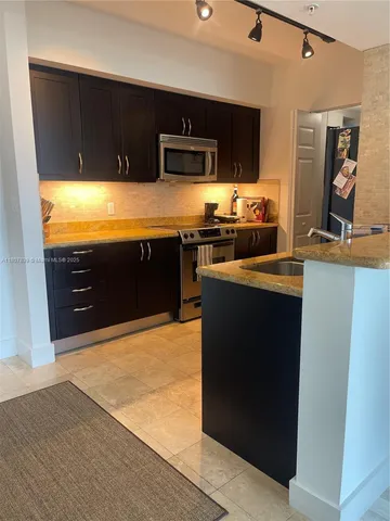 a kitchen with stainless steel appliances granite countertop a stove a sink and a microwave