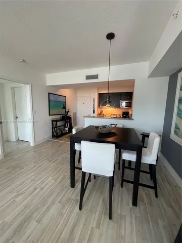 a kitchen with kitchen island a dining table chairs and a wooden floor