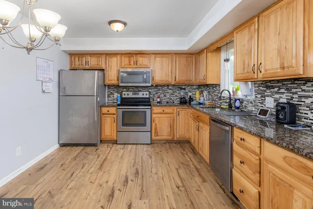 a kitchen with stainless steel appliances granite countertop a stove a sink dishwasher and a refrigerator with wooden floor