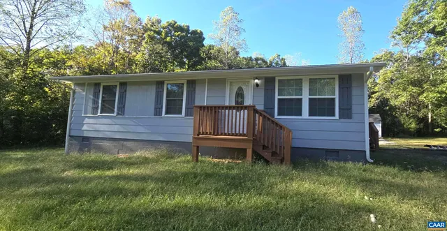 a backyard of a house with wooden deck and outdoor seating