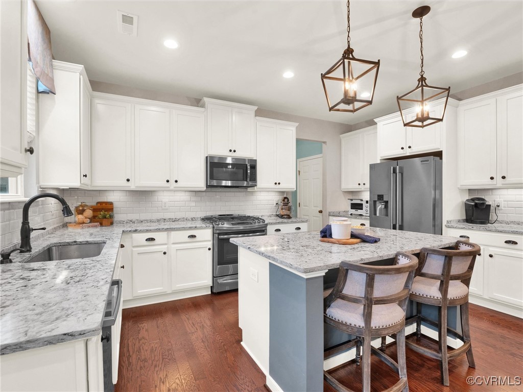 10168 Kellys Bluff Run Ashland, VA 23005 - Photo 13 of 50 a kitchen with stainless steel appliances granite countertop a sink a stove a refrigerator cabinets a dining table and chairs