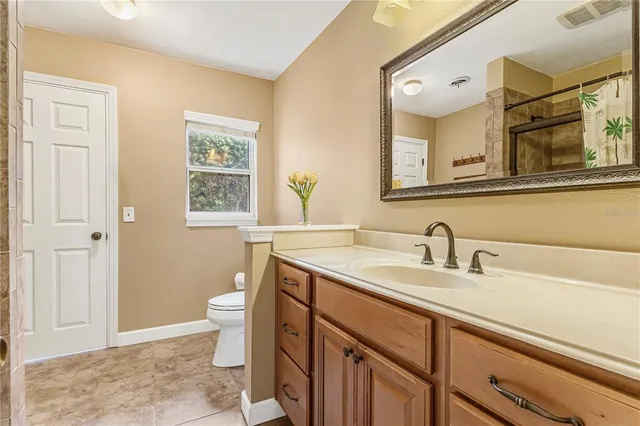 a bathroom with a granite countertop sink a mirror a bathtub and next to a window