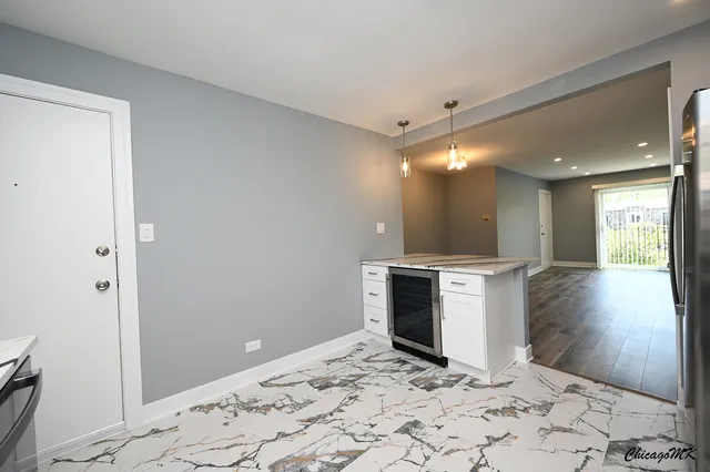 a view of a hallway with wooden floor and a kitchen space