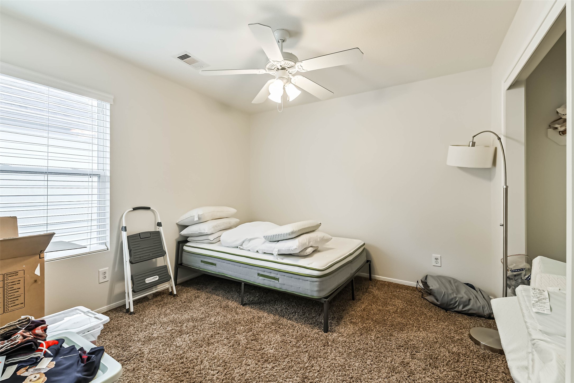 22538 Goss Spring Court Spring, TX 77373 - Photo 31 of 36 This room features neutral walls, carpeted flooring, and a ceiling fan with lights. It includes a window for natural light, a basic bed setup, and a floor lamp. Minimal furnishings provide a blank canvas for personal touches.