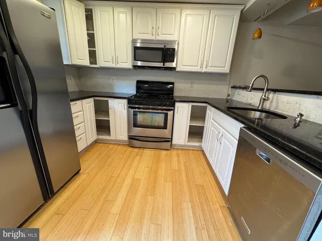 a kitchen with granite countertop wooden floors and stainless steel appliances