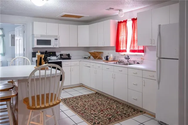 a kitchen with a refrigerator a stove a sink cabinets and a dining table