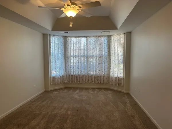 en empty room with windows and chandelier fan