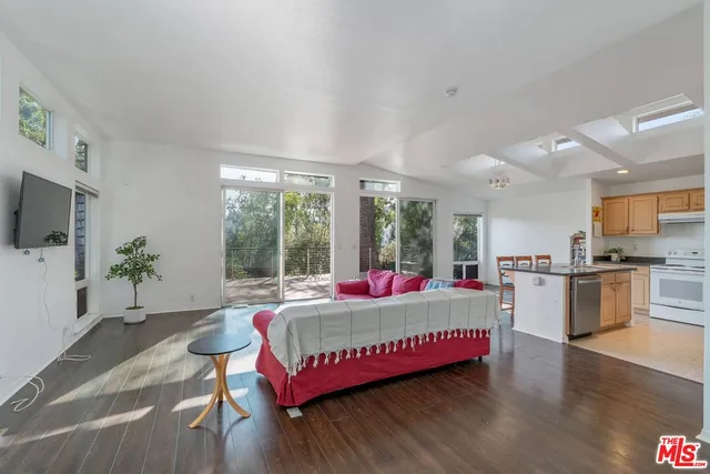 a living room with kitchen and a wooden floor