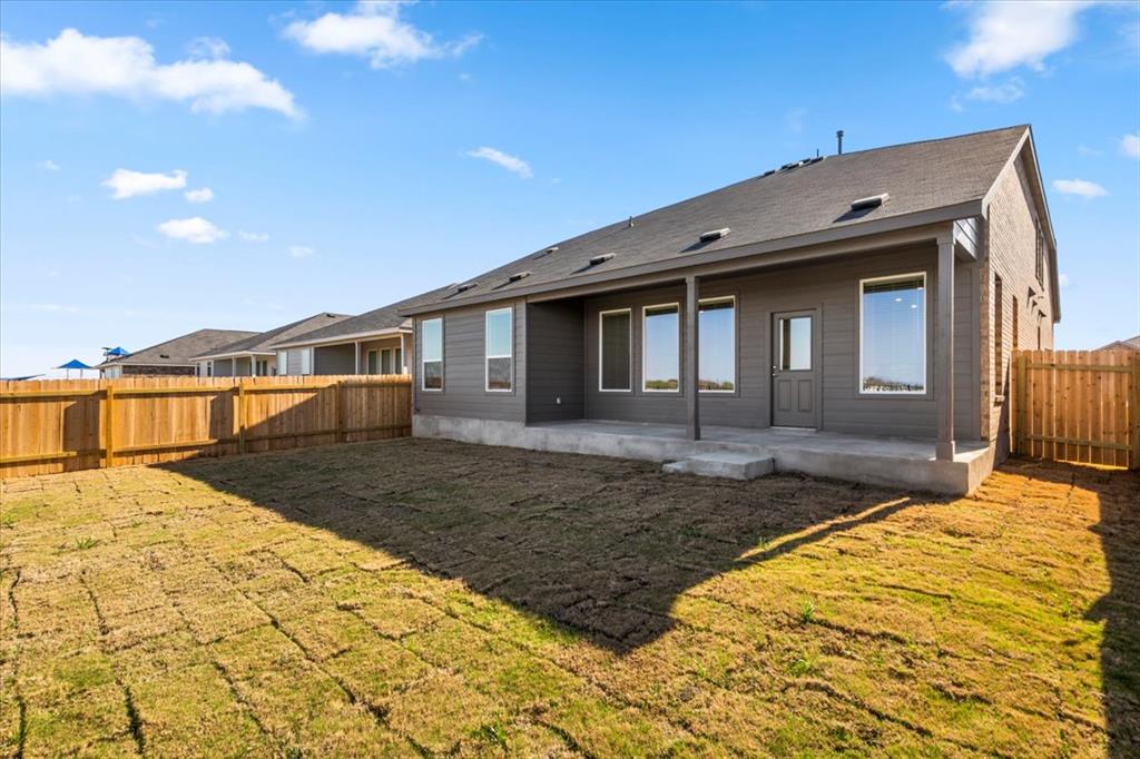 192 Rodney Boat Road Kyle, TX 78640 - Photo 37 of 38 A fenced backyard offers a concrete patio with a covered area, ideal for relaxation.