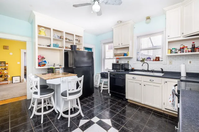 a kitchen with stainless steel appliances a sink a stove a refrigerator cabinets and dining table