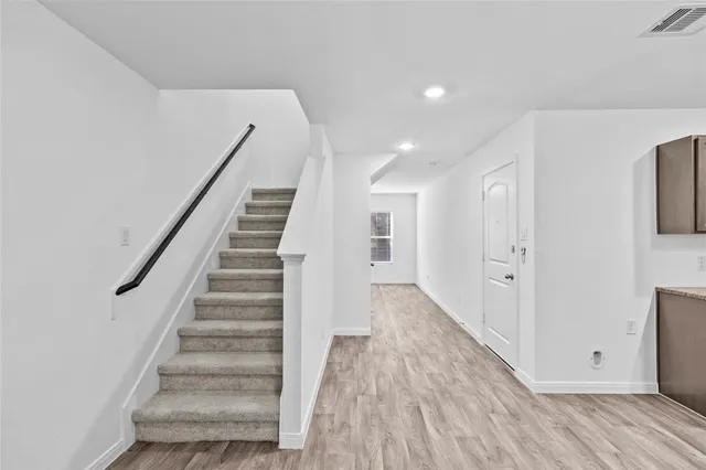 a view of a hallway with wooden floor and staircase