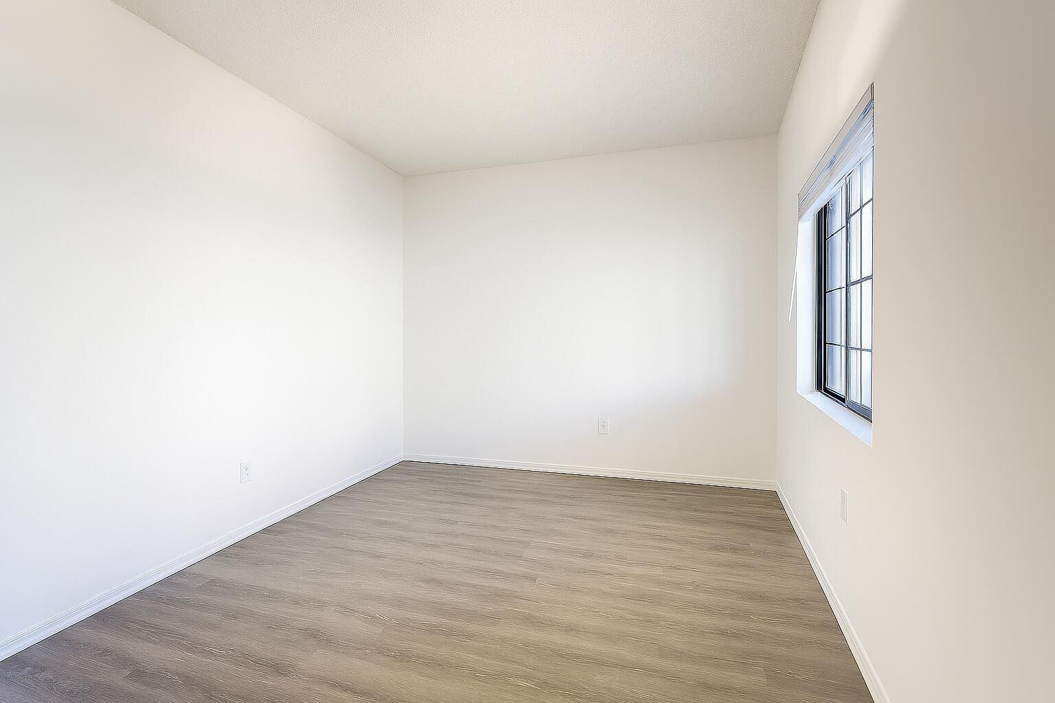 4685 Haverhill Road, Unit A8 West Palm Beach, FL 33417 - Photo 17 of 33 an empty room with wooden floor and windows