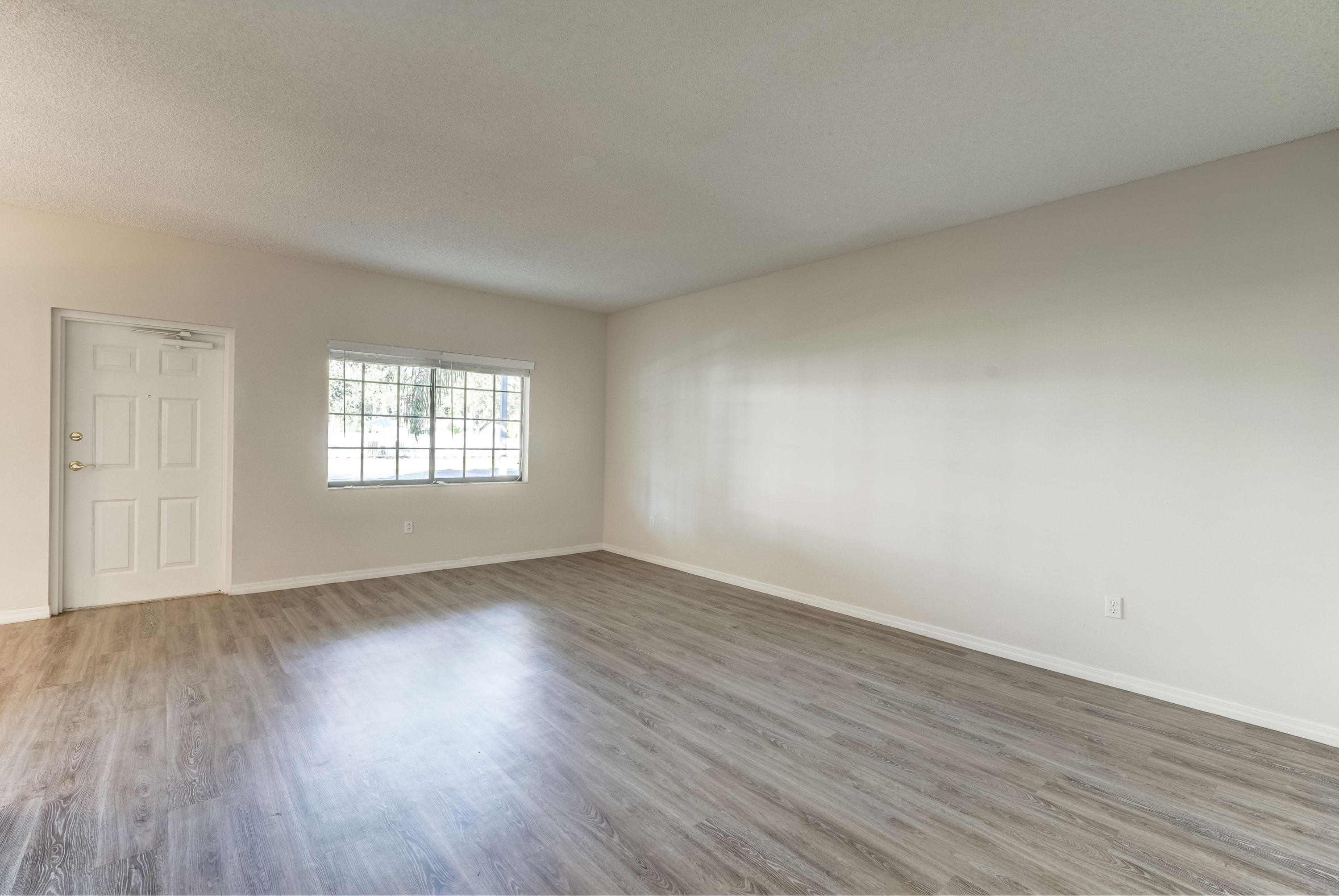 4685 Haverhill Road, Unit A8 West Palm Beach, FL 33417 - Photo 4 of 33 an empty room with wooden floor and windows