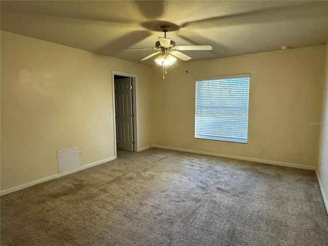 an empty room with a chandelier fan and windows