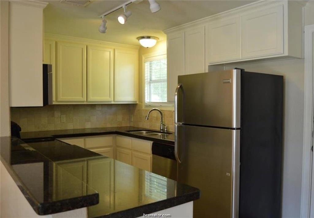 4309 Old College Road Bryan, TX 77801 - Photo 5 of 10 Kitchen featuring dark stone countertops, light cabinetry, and a tile backsplash