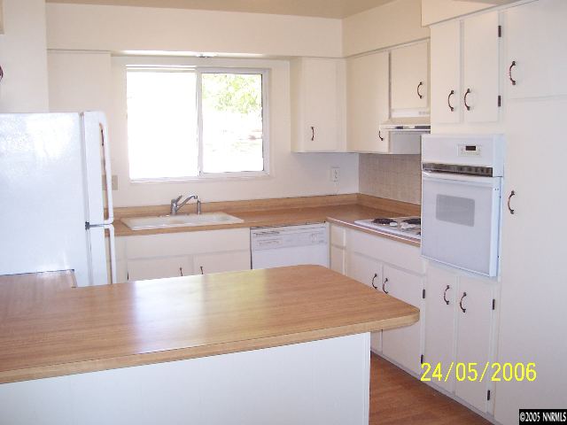 460 Tarn Way Reno, NV 89503 - Photo 3 of 4 a kitchen with stainless steel appliances granite countertop a sink and white cabinets